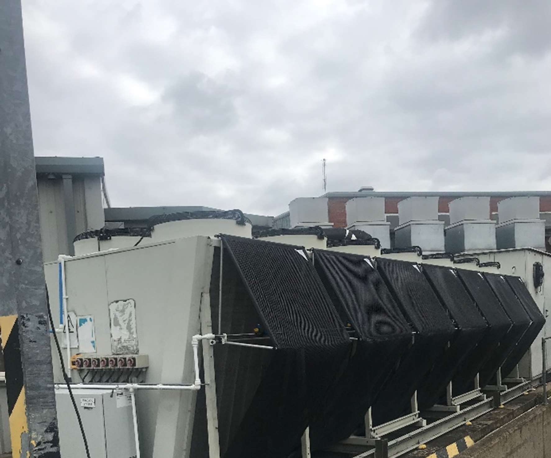A row of air-cooled chillers fitted with iMESH adiabatic pre-cooling screens across their condenser faces