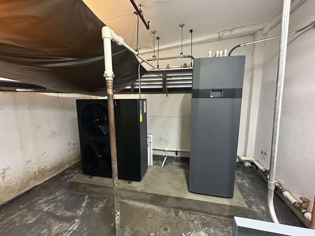 Finished installation: iHEAT R290 heat pump and iSTOR hot water store side by side on a concrete plinth, piped up