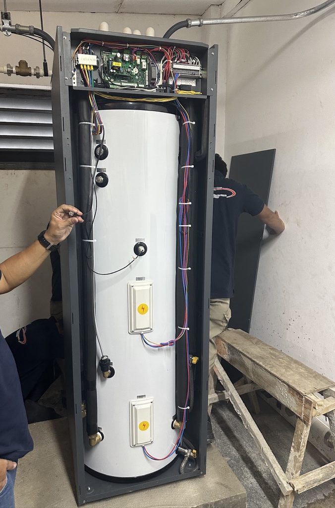 Karnot engineer wiring the sensors on an iSTOR hot water store with the cabinet open and the controller visible on top