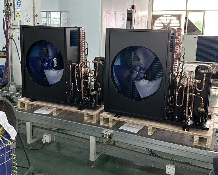 Two compact single-fan heat pump monoblocs on pallets with copper pipework exposed at the rear