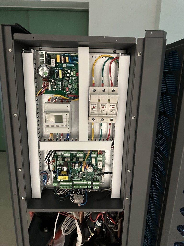 Open electrical panel of a heat pump showing controller, energy meter and isolators