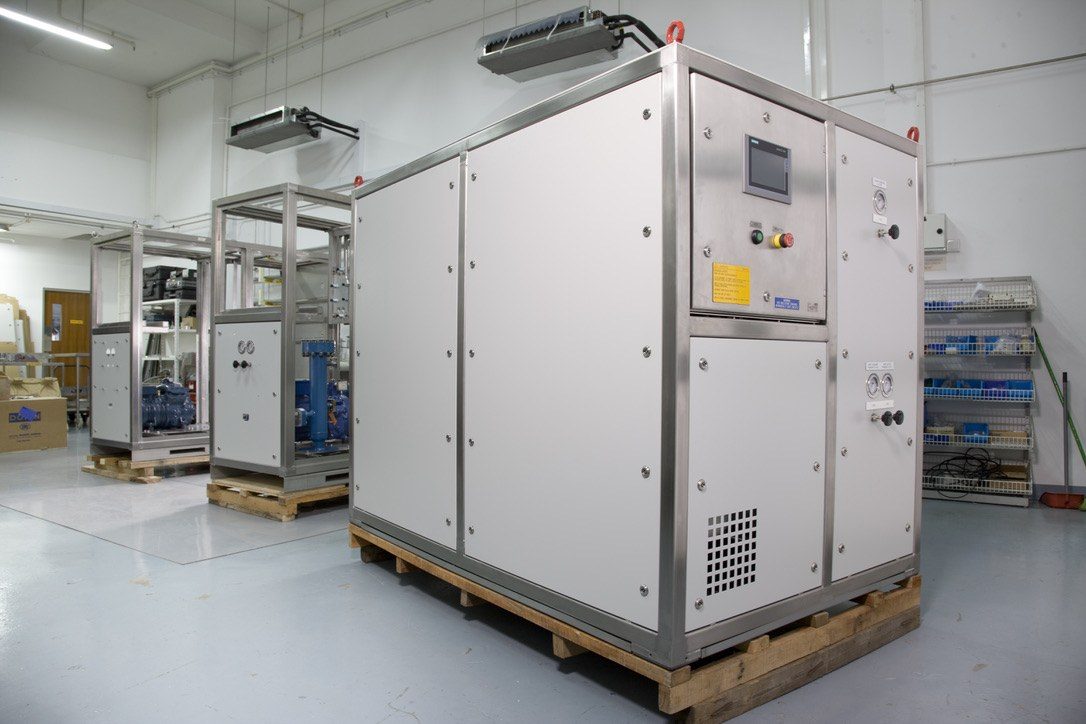 Three packaged heat pump units on pallets in a clean workshop